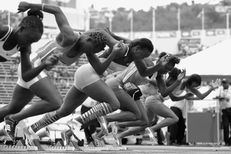 High school girls coming out of the blocks during a 100-meter dash race.