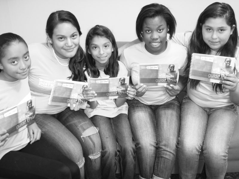 Participants in the Go Girl Go program holding up the Go Girl Go Guide to Life.