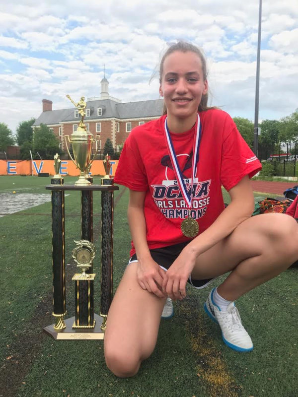 A young lacrosse player poses with her trophy